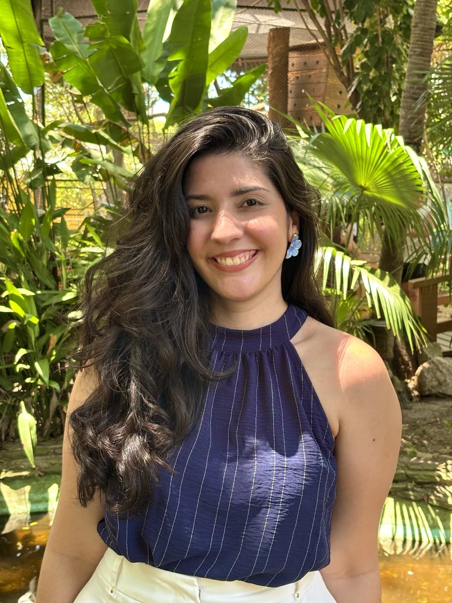 Julie Caroline sorrindo em um ambiente com plantas